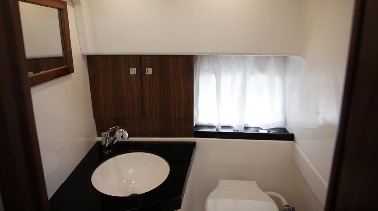Lockable shower-toilet compartment with ventilation portlight, Corian sinktop and storage lockers